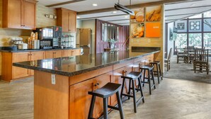 A spacious kitchen with wooden cabinets, a large island with bar stools, a coffee machine, and a refrigerator. - Comfort Inn Flagstaff South I-17 (Flagstaff)