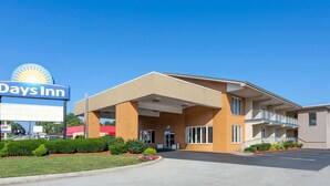 Un bâtiment de la chaîne Days Inn, avec une entrée bien visible, un parking et un espace paysager agrémenté d’arbustes et de fleurs.