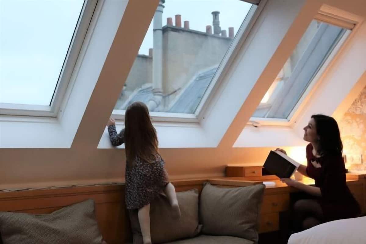 Una habitación con tragaluz, un sofá y una mesita de noche.