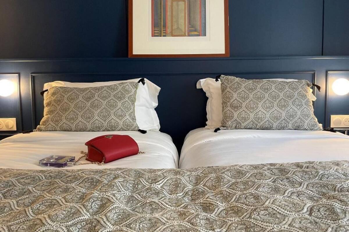 Habitación de hotel con dos camas, una obra de arte enmarcada encima y lámparas de noche.