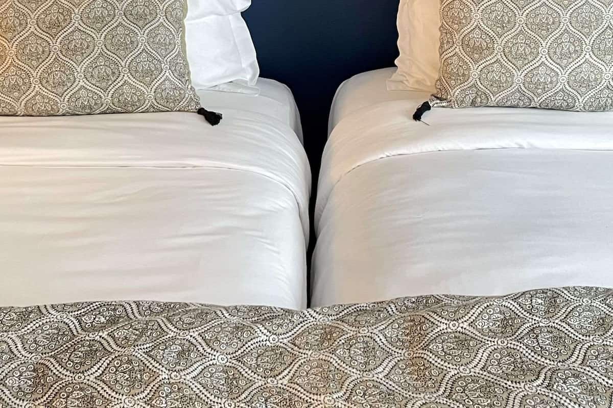 Una cama doble con almohadas estampadas y una obra enmarcada en la pared de arriba.