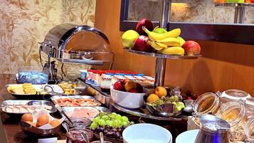 A buffet with various food items including fruits, meats, and condiments.
