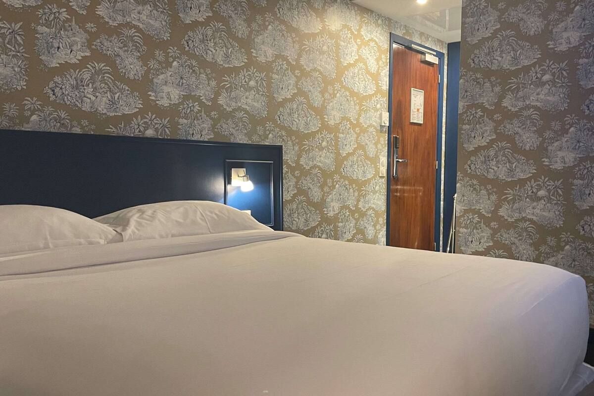 Una habitación de hotel con una cama, una mesita de noche y una puerta.