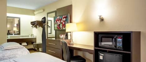 A hotel room with two beds, a desk with a computer, a microwave, a refrigerator, a mirror, and a television.