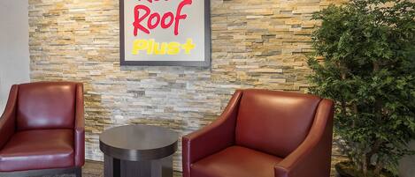 A Red Roof Plus lounge area with two leather armchairs and a small round table.