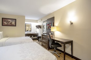 A hotel room with two beds, a desk, a chair, a desk lamp, a mirror, and a wall-mounted TV. - Red Roof Inn PLUS+ Boston - Framingham (Framingham)
