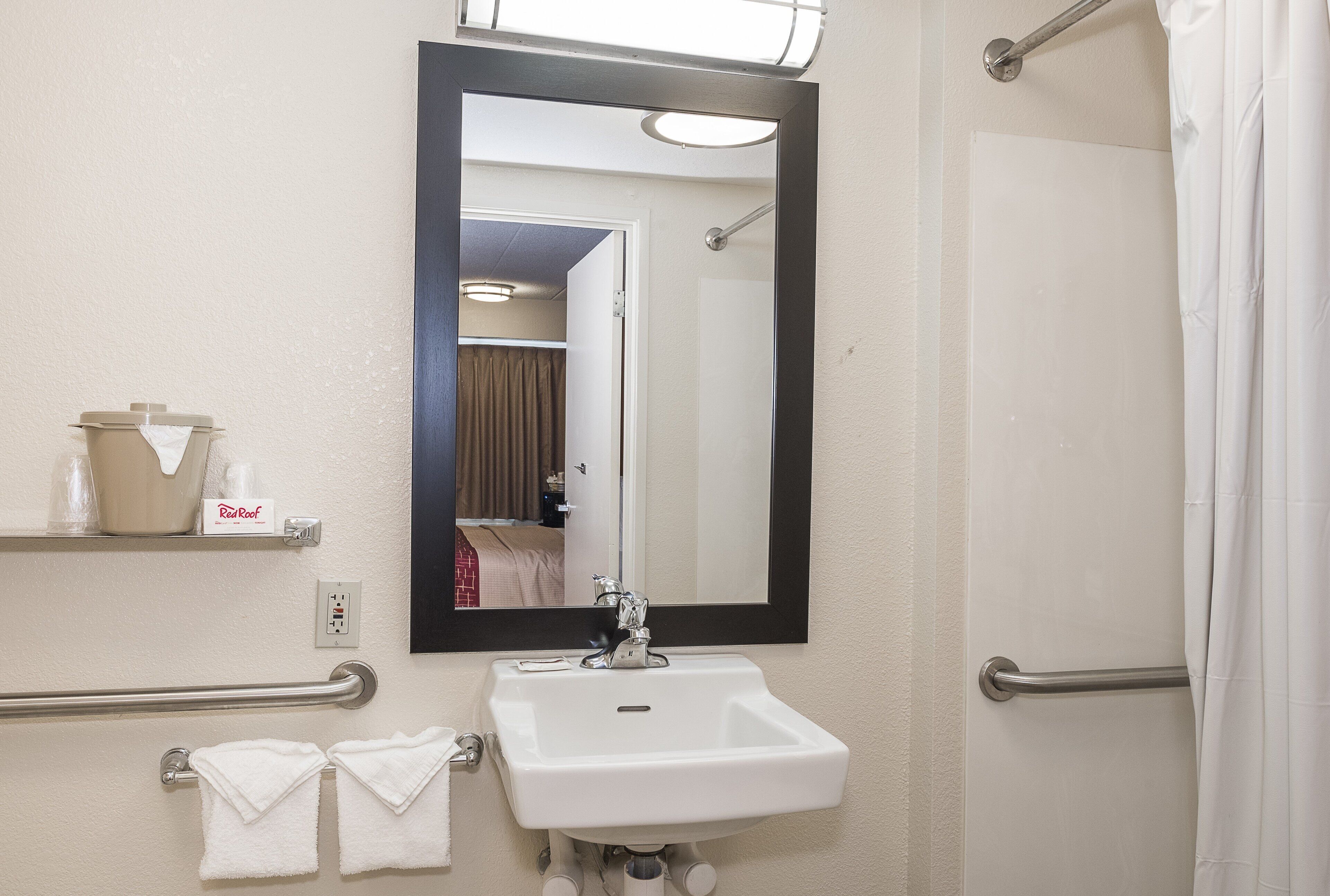 Un baño con lavamanos, espejo, toallero y cortina de ducha.