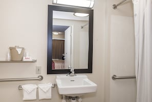 A bathroom with a white sink, a large mirror, and a towel rack. - Red Roof Inn PLUS+ Boston - Framingham (Framingham)