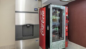 A vending machine and a refrigerator in a room with a tiled floor and a red wall. - Red Roof Inn PLUS+ Boston - Framingham (Framingham)