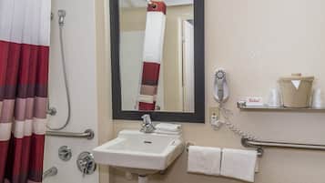 A bathroom with a white sink, a mirror, a shower curtain, a towel rack, and a telephone.