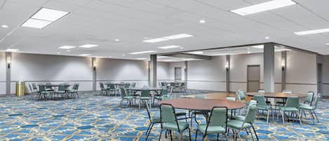 A conference room with tables and chairs, a patterned carpet, and a white ceiling with lights.