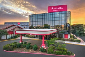 A modern building with a prominent red sign reading 'RAMADA BY WYNDHAM' and a gas station canopy in front. - Ramada by Wyndham Tulsa Broken Arrow (Broken Arrow)