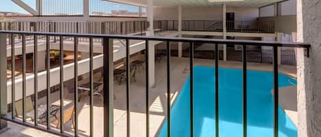 A multi-level outdoor swimming pool with a metal railing, surrounded by tables and chairs.