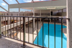 A multi-level outdoor swimming pool with a metal railing, surrounded by tables and chairs. - Ramada by Wyndham Tulsa Broken Arrow (Broken Arrow)