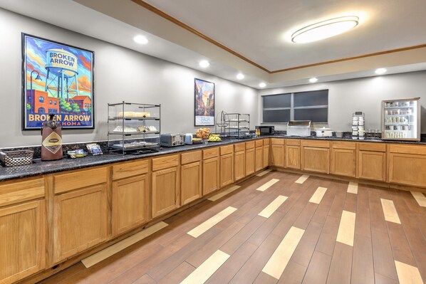 A spacious kitchen with wooden cabinets, a marble countertop, and various appliances.