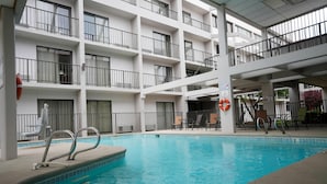 A hotel pool area with a clear view of the pool, lounge chairs, and a multi-level balcony. - Ramada by Wyndham Tulsa Broken Arrow (Broken Arrow)