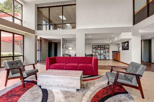 Un vestíbulo amplio con un sofá rojo, sillones grises y una mesa de centro.