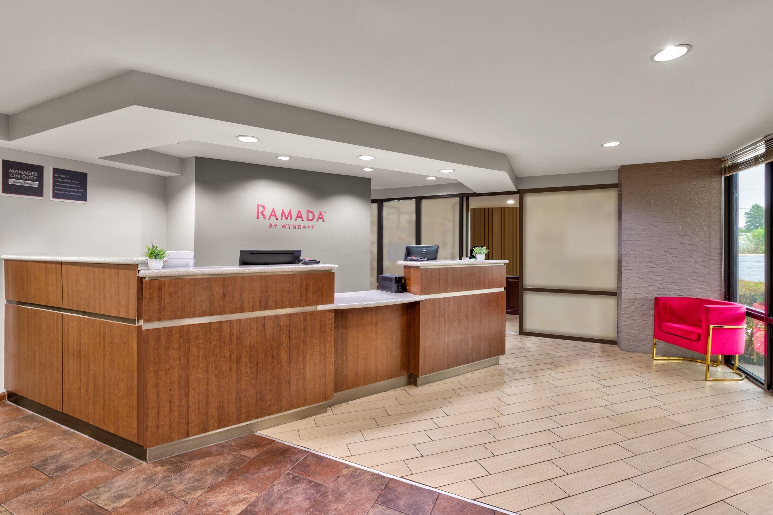 A reception area with a wooden reception desk, a computer, and a red chair.