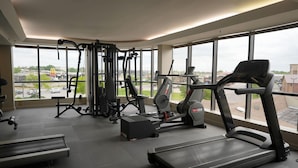 A gym with various exercise equipment, large windows, and a view of the outside. - Ramada by Wyndham Tulsa Broken Arrow (Broken Arrow)