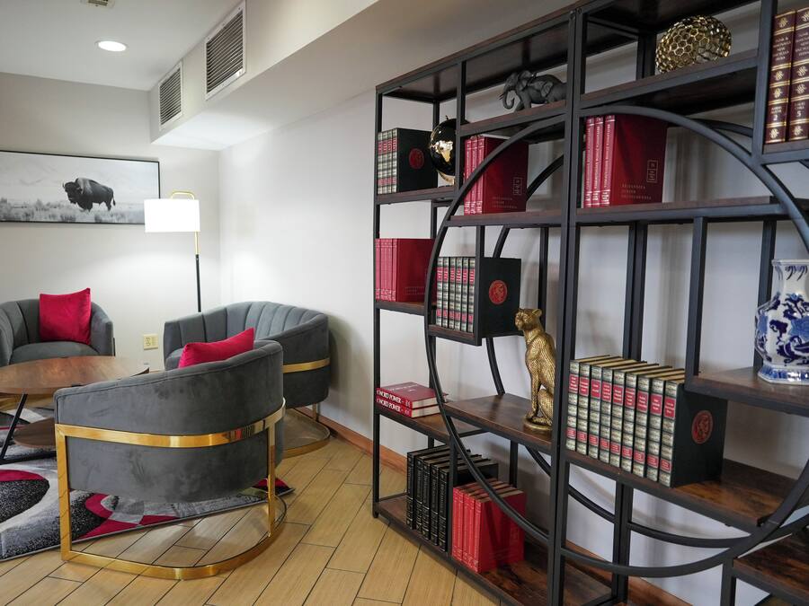 A modern living room with two grey armchairs, a coffee table, a bookshelf, and a mounted artwork of a bison.