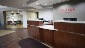 A reception area with a desk, a computer, and a wall sign reading 'RAMADA BY WYNDHAM'. - Ramada by Wyndham Tulsa Broken Arrow (Broken Arrow)