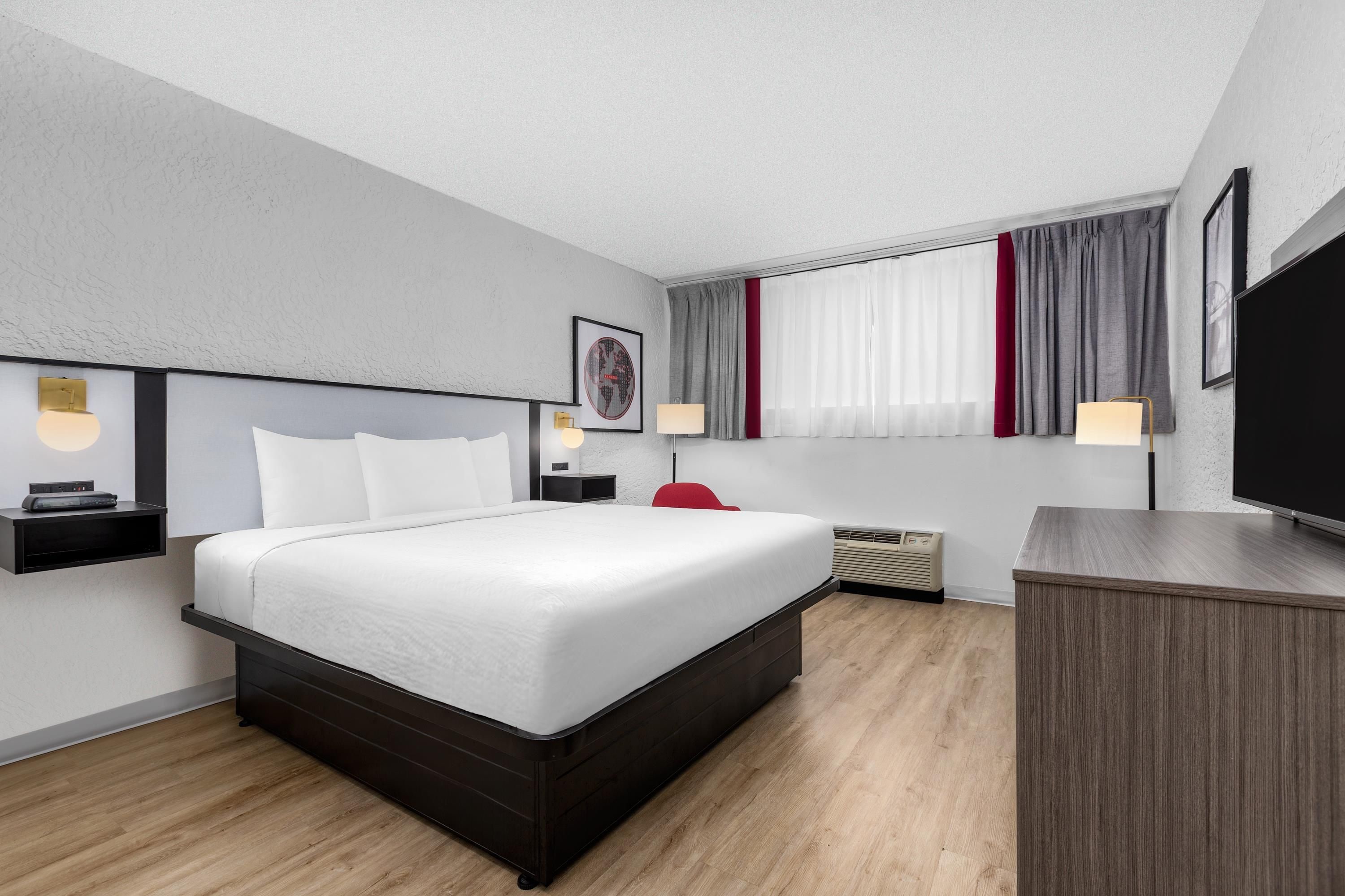 Una habitación de hotel moderna con una cama grande, mesitas de noche, un televisor y un escritorio.