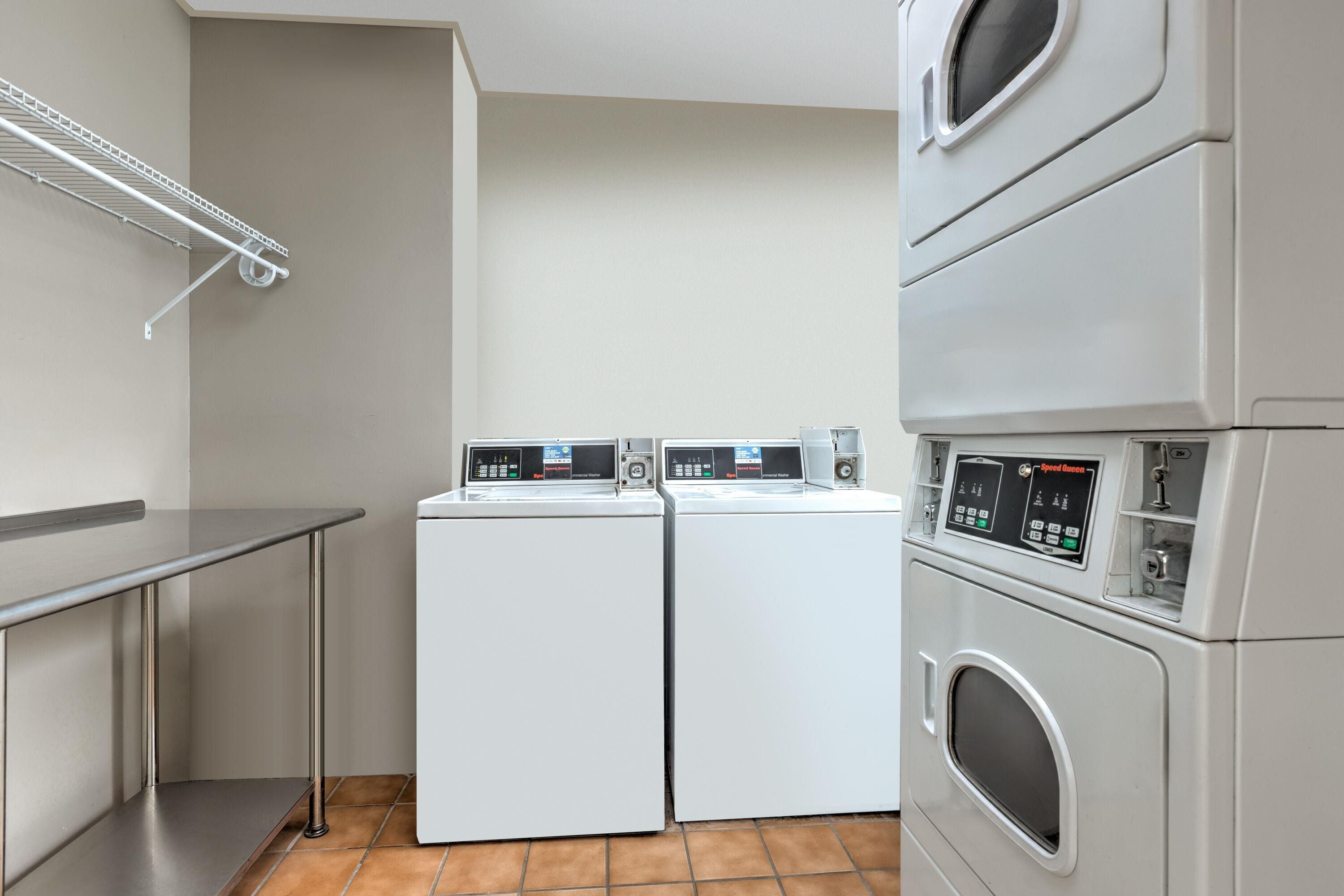A laundry room with two front-loading washers and a stacked dryer.