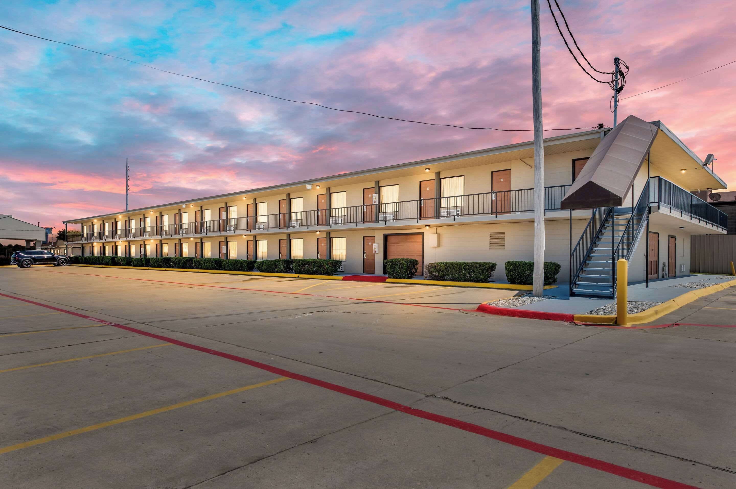 A motel with a two-story structure, multiple rooms, and a staircase leading to the upper level.
