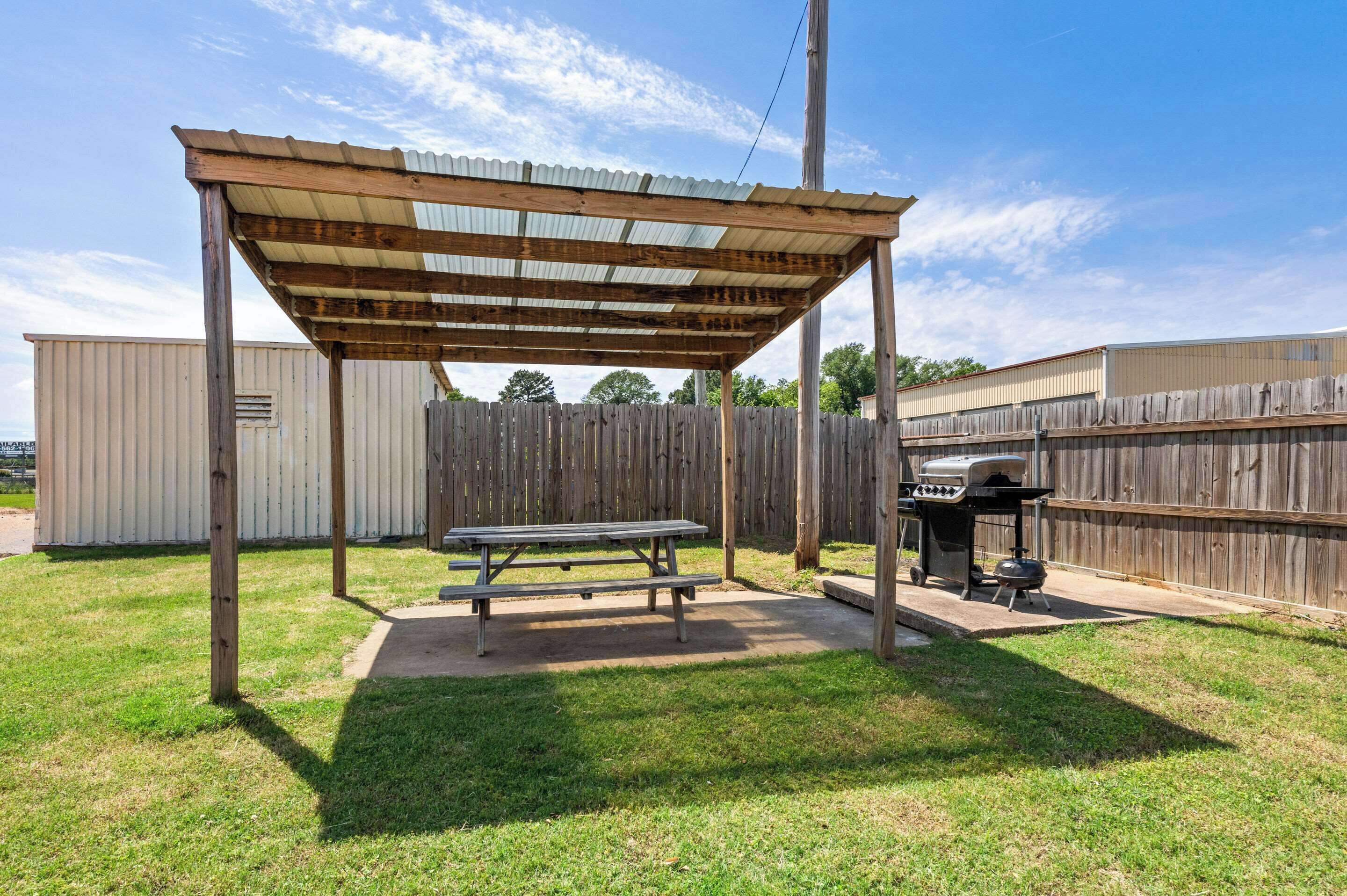 A covered picnic area with a grill and a picnic table.