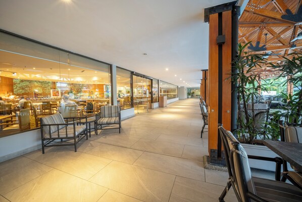 A spacious indoor area with seating arrangements and a view of a restaurant through glass walls. - InterContinental Cali by IHG (Cali)
