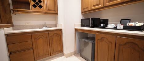 A kitchen with wooden cabinets, a microwave, a coffee maker, and a trash bin.