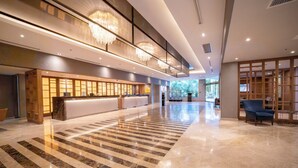 A spacious lobby with a reception desk, chandeliers, and a large marble floor.