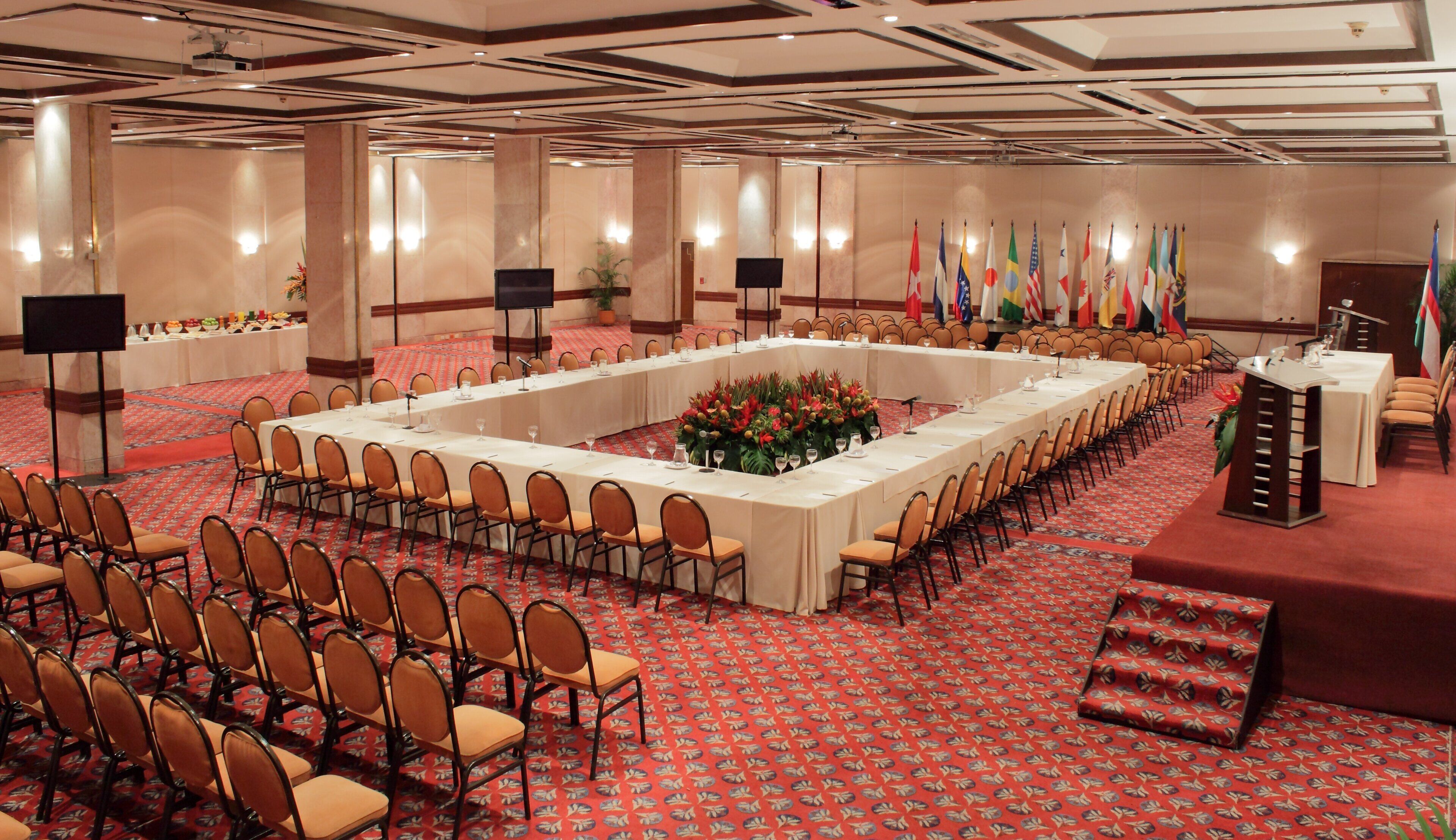 A conference room with a long table, chairs, and a podium.