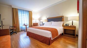 A hotel room with a large bed, bedside tables, a desk, and a chair.