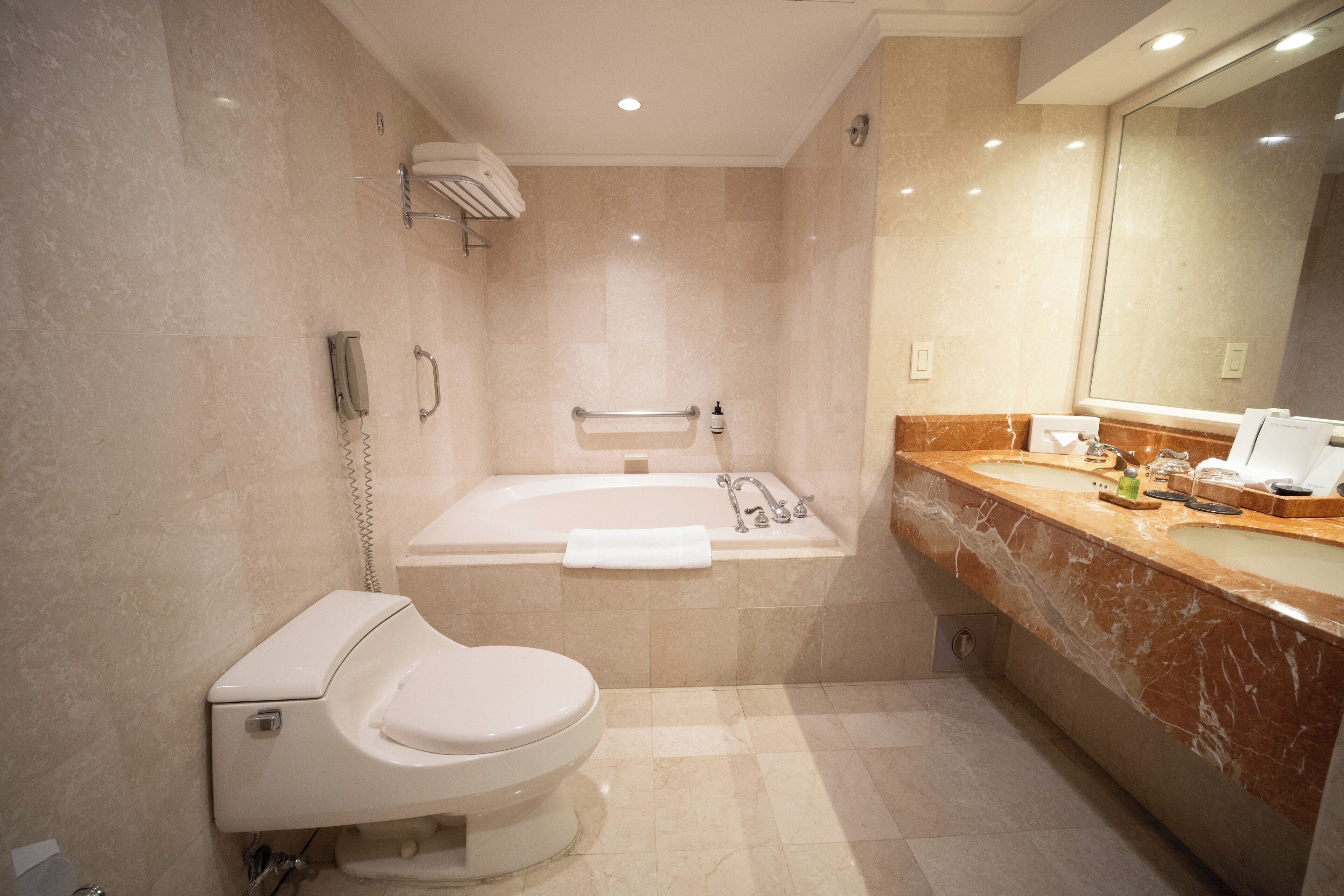 A modern bathroom with a toilet, a bathtub, and a vanity with a mirror.
