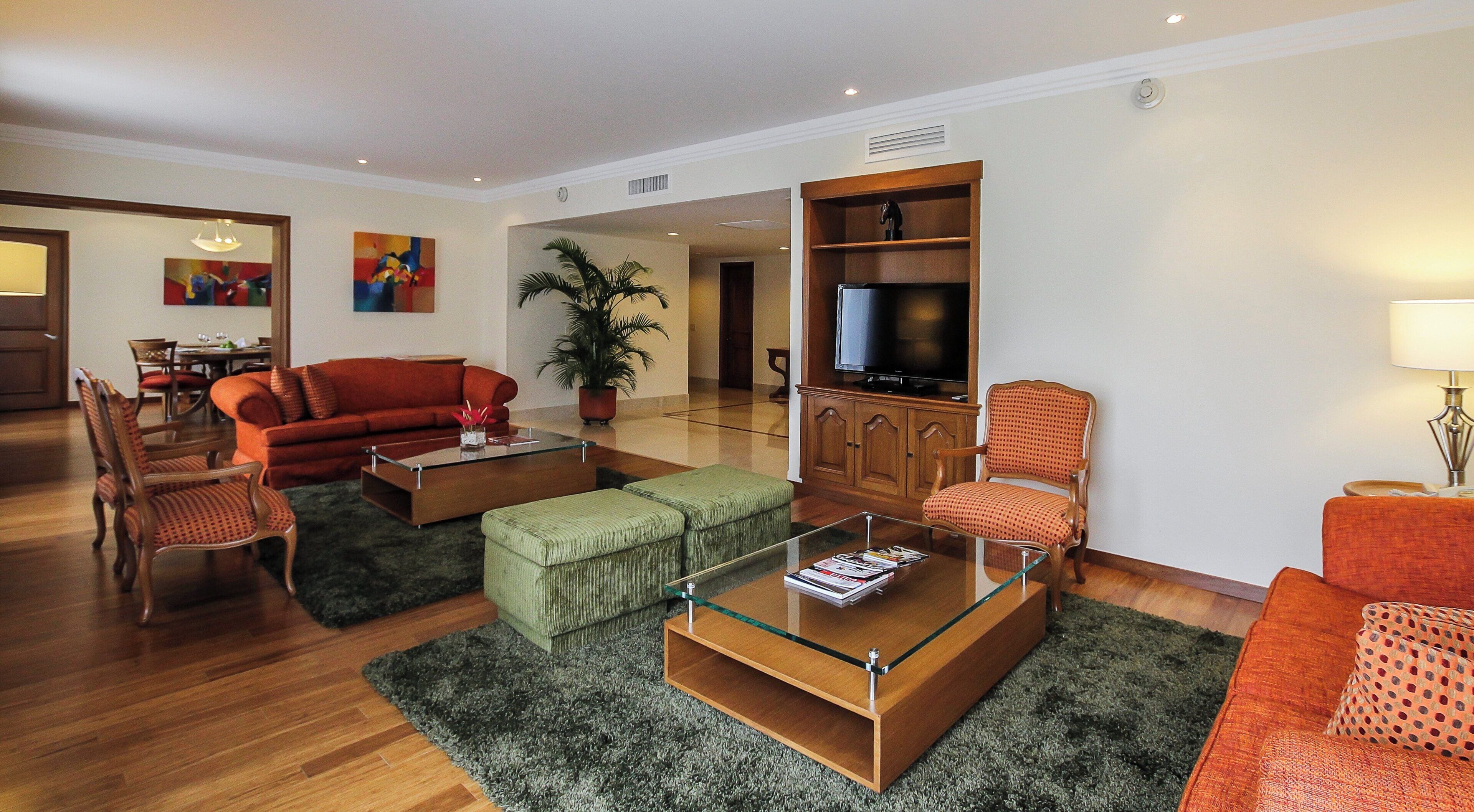 A modern living room with a sofa, ottoman, coffee table, and a television.