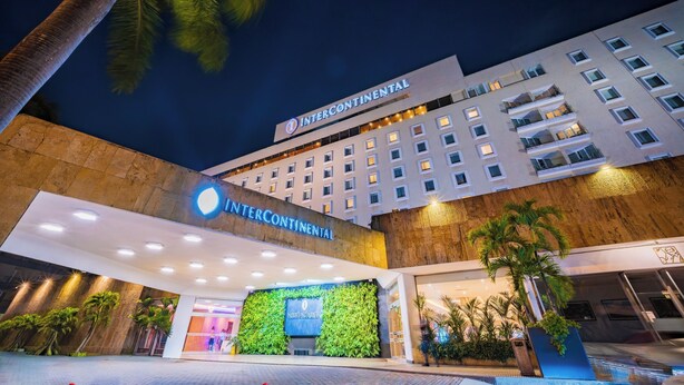 A hotel with a modern facade, a prominent sign, and a landscaped entrance area.