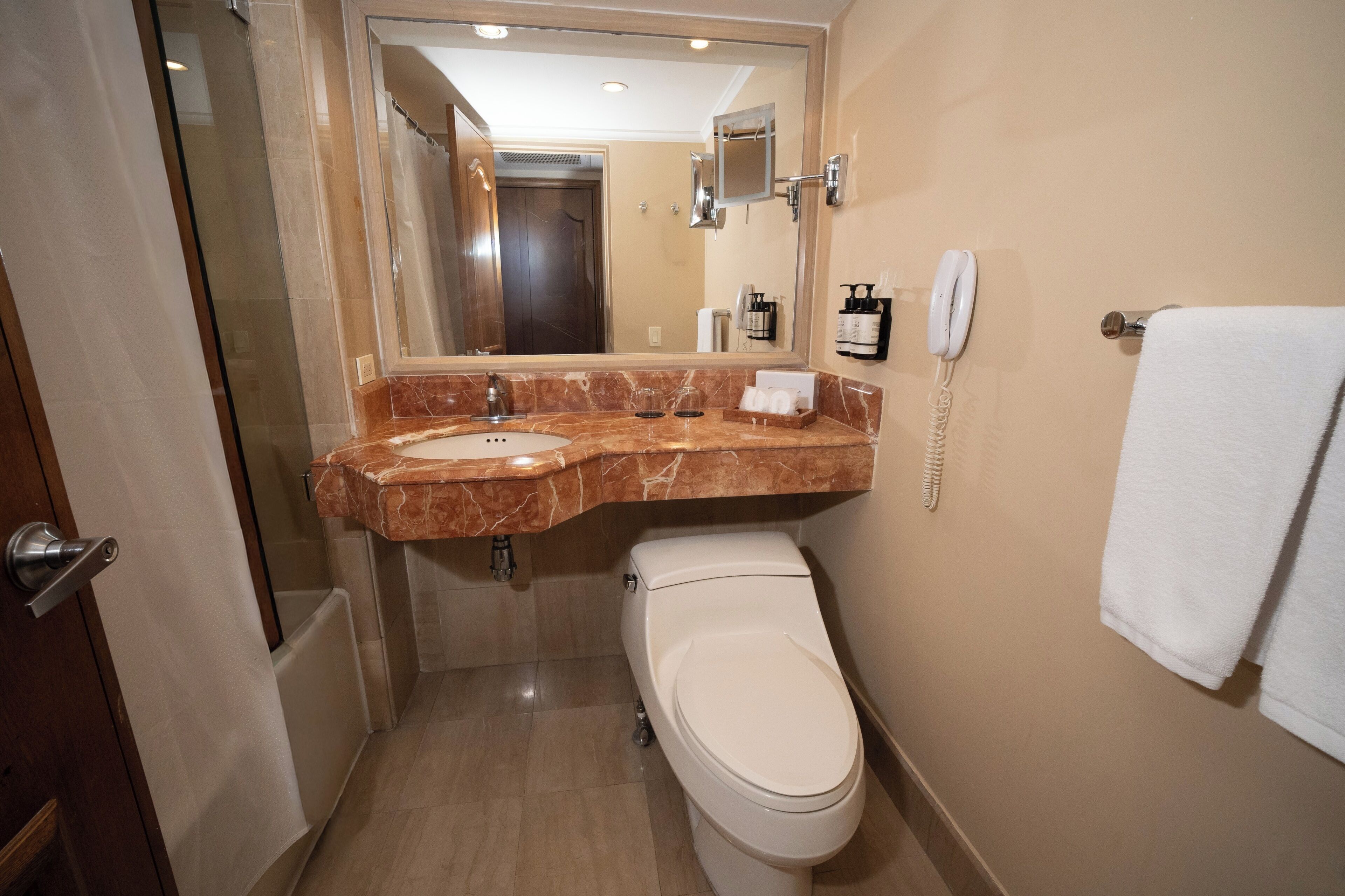 Ein Badezimmer mit Marmorbecken, Toilette, Handtuchhalter und Spiegel.