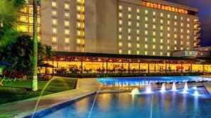 Un hotel con piscina, mobiliario exterior y una fachada bien iluminada.
