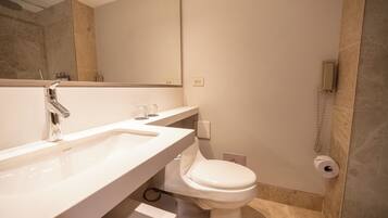 A bathroom with a white sink, a toilet, and a shower area.