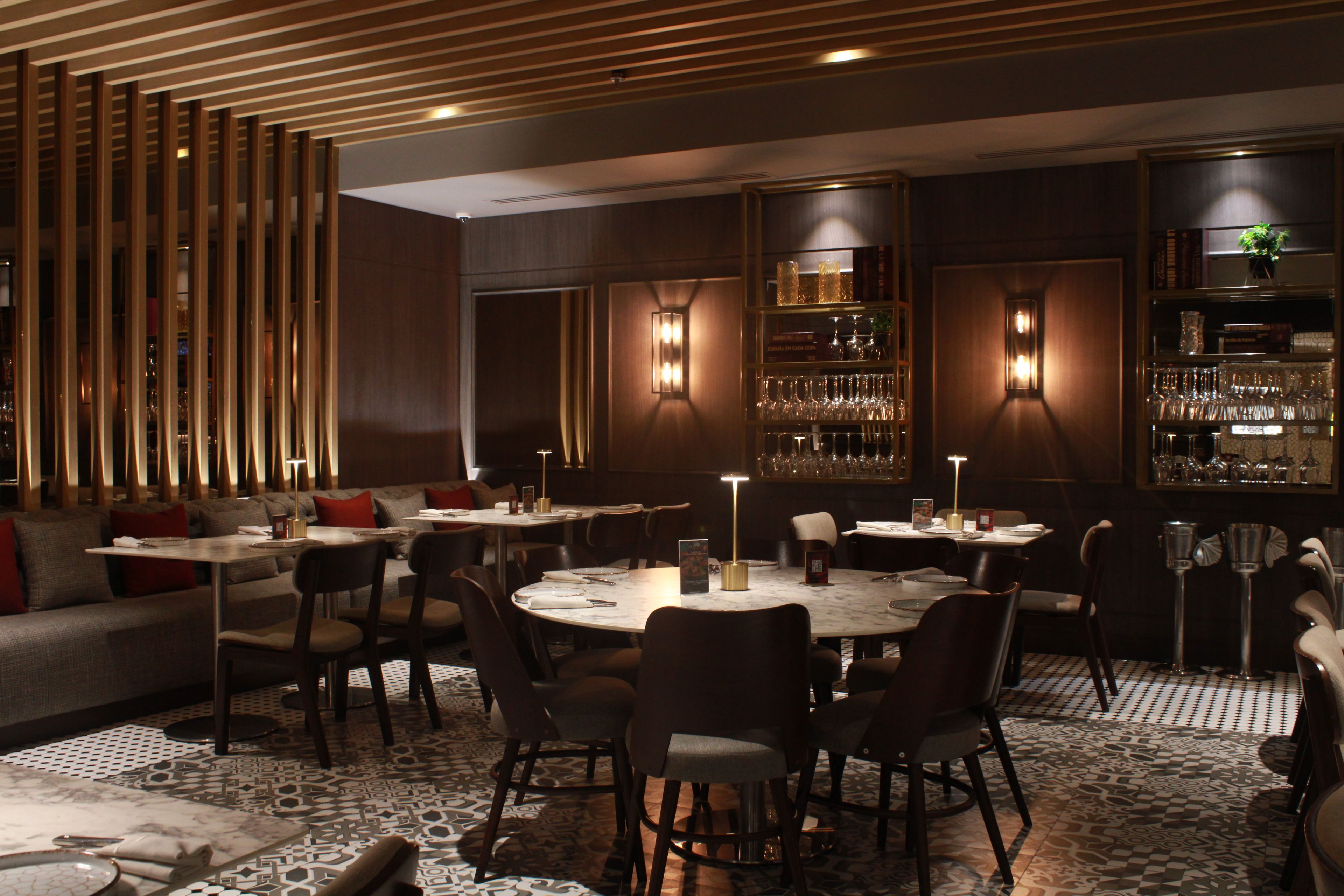 Een restaurant met ronde tafels, stoelen en een bar met glazen kasten.