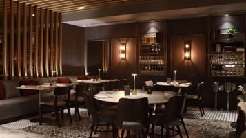 Een restaurant met ronde tafels, stoelen en een bar met glazen kasten.
