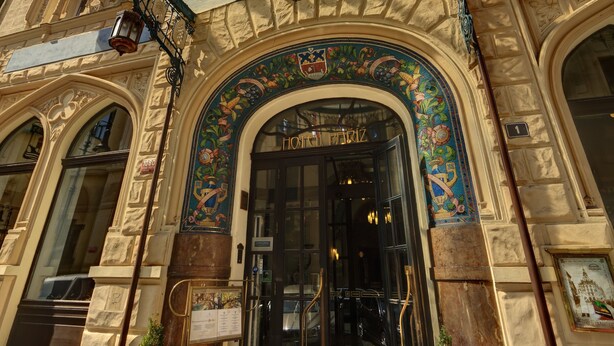 A grand entrance with a glass canopy, ornate decorations, and multiple flags. - Hotel Paris Prague (Prague)