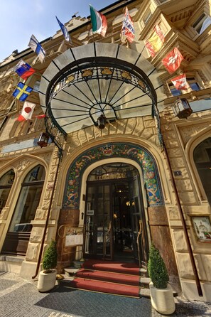 A grand entrance with a glass canopy, ornate decorations, and multiple flags. - Hotel Paris Prague (Prague)