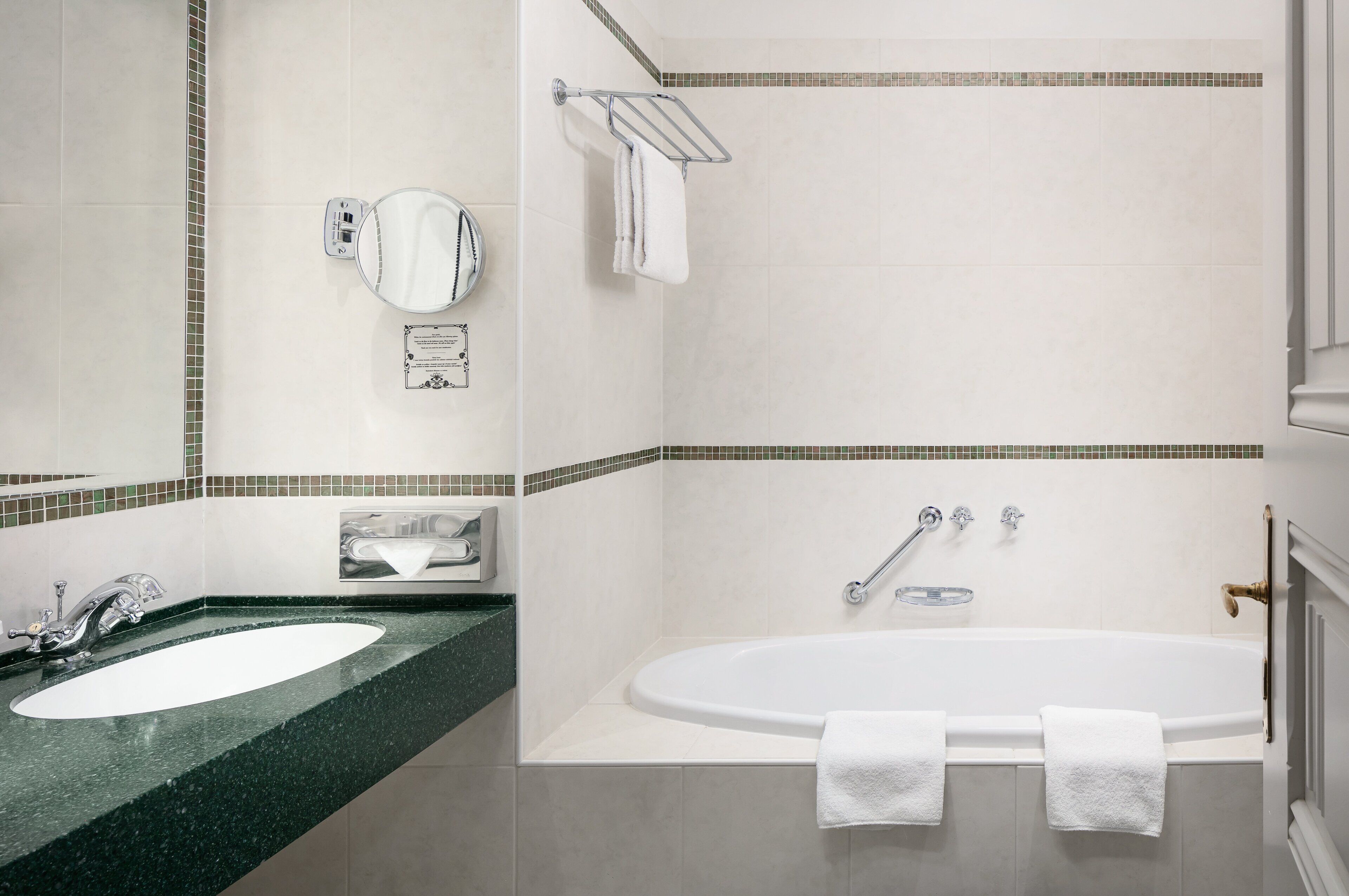 Une salle de bain équipée d’un lavabo, d’un miroir, d’un porte-serviettes et d’une baignoire.