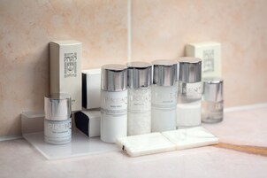 Diversos produtos de cuidados com a pele, incluindo loção corporal, condicionador de cabelo e gel de banho, dispostos numa bancada.