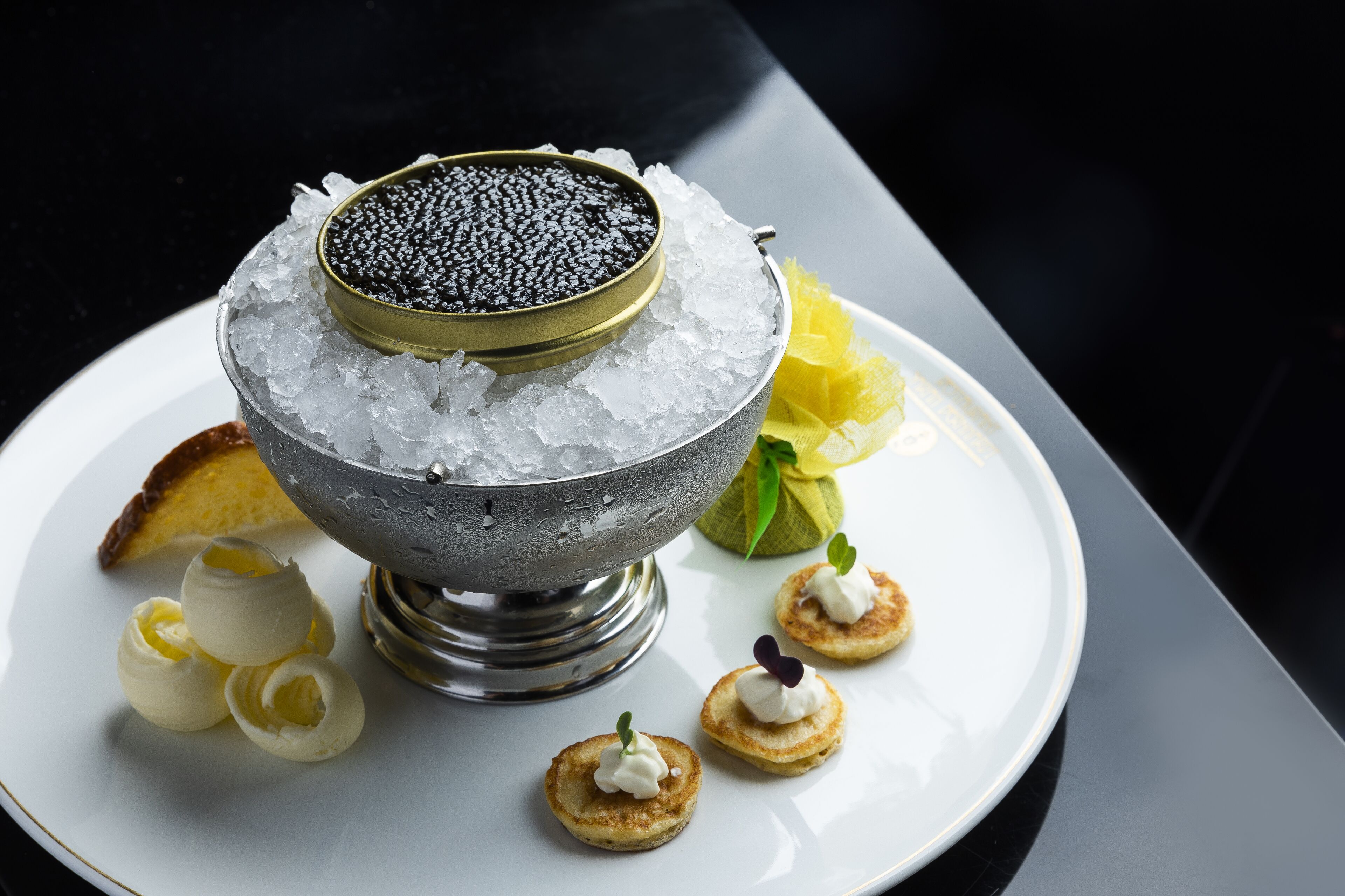Un dessert con gelato e caviale, guarnito con fette di limone e piccole quenelle di crema.