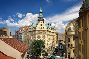 A historic building with ornate architecture, a prominent tower, and a street lined with parked cars. - Hotel Paris Prague (Prague)