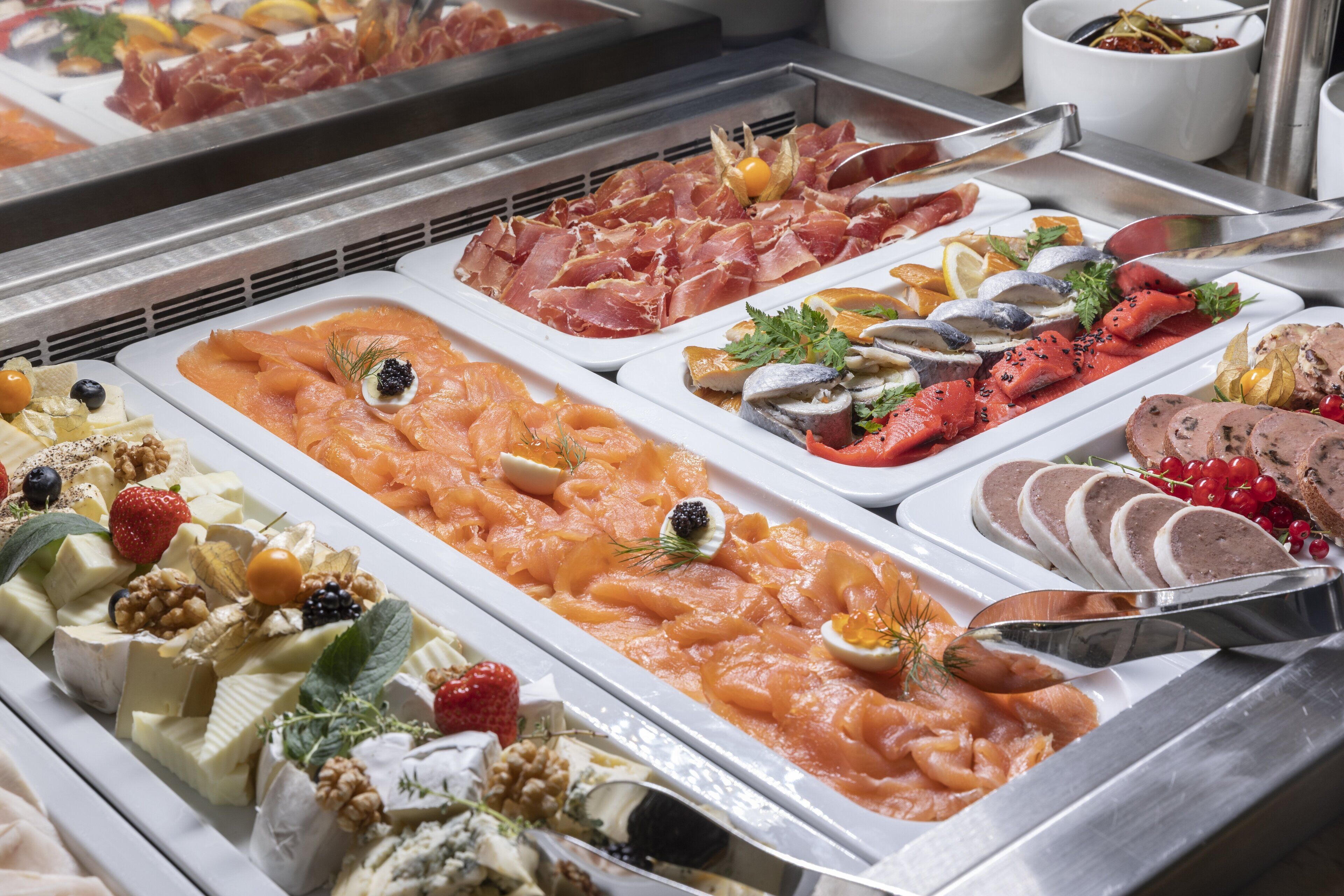 A buffet with various food items including smoked salmon, cheeses, and fruits.