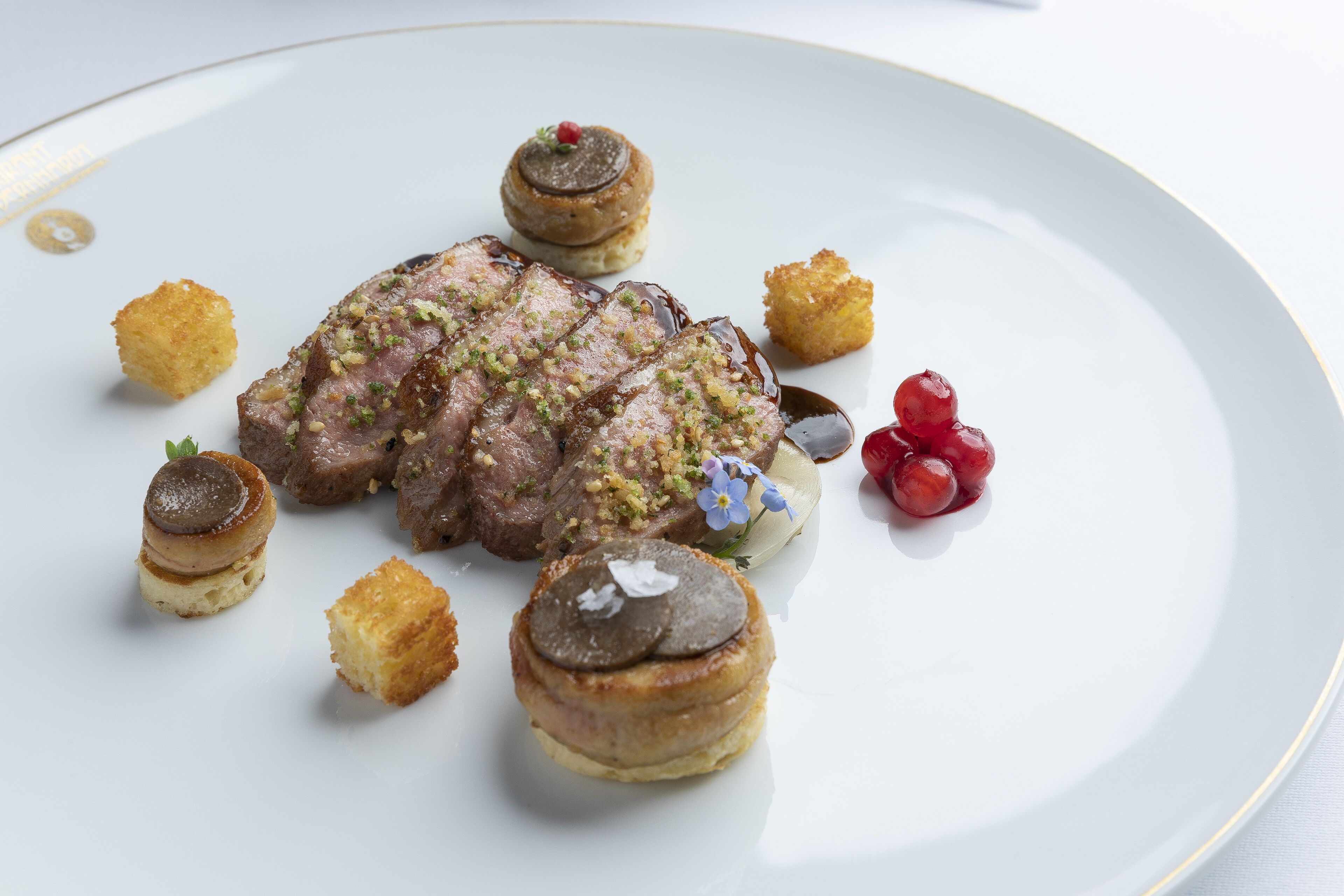 Um prato com bife, cogumelos e frutas vermelhas.